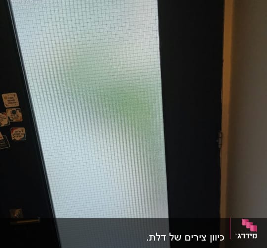 דלת מקלט כהה עם חלון זכוכית מחוזקת ברשת מתכת
